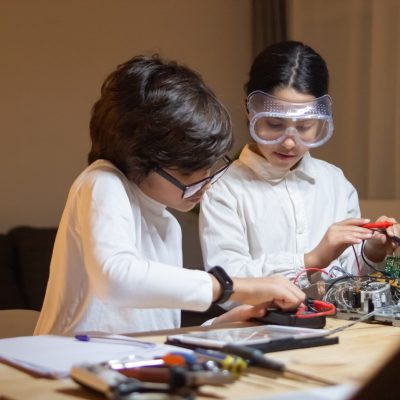 Focused children doing experiment in physics together in school lab. Girl and boy taking measurements. Education, hobby, school concept